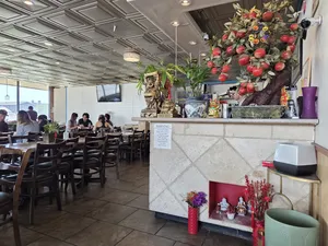 A view of the restaurant's interior, with customers seated at tables and a decorative display near the counter, including a tree with apples and traditional Vietnamese decorations.